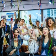 Corporate celebration with professionally dressed guests raising champagne glasses in a modern event venue.