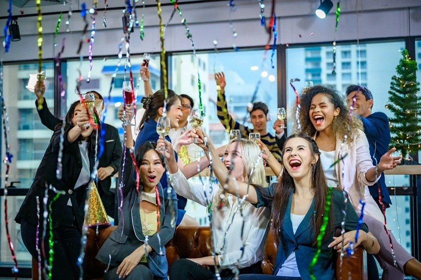 Corporate celebration with professionally dressed guests raising champagne glasses in a modern event venue.