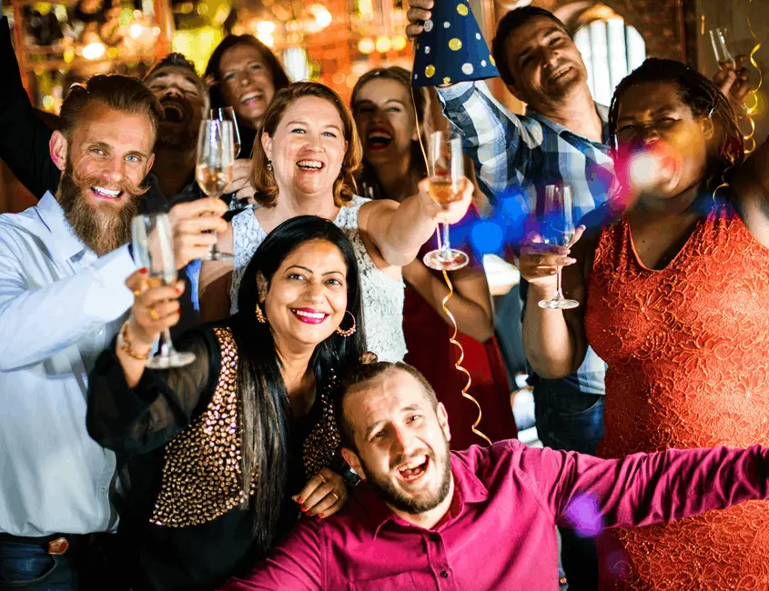 Group of guests smiling and raising champagne glasses while celebrating together at a lively private party.