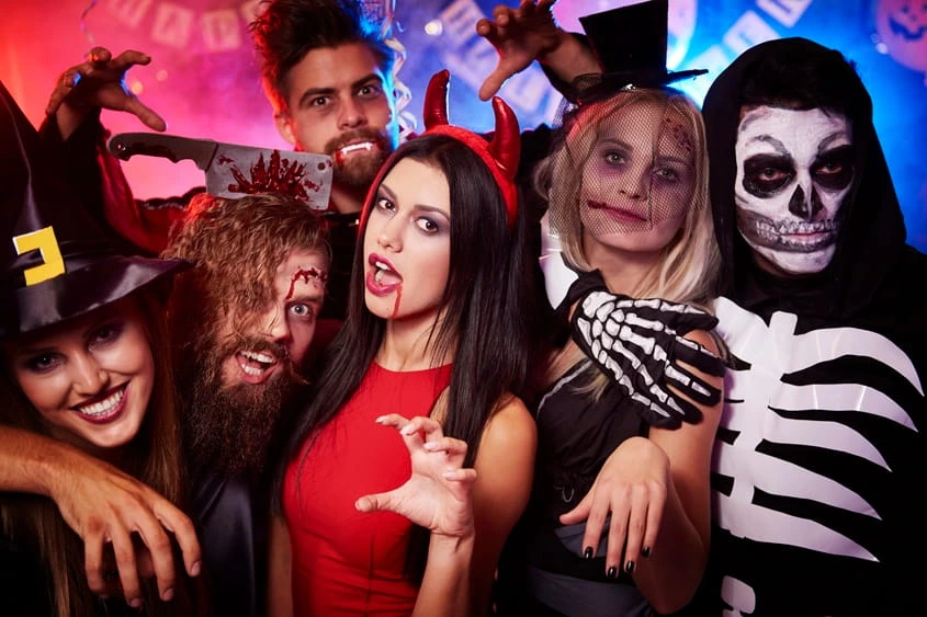 Guests dressed in Halloween costumes posing and celebrating together at a themed private party.