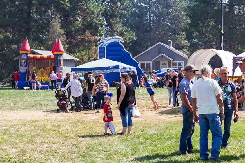 Families and friends gathering at an outdoor community event with inflatable attractions and activities for children.